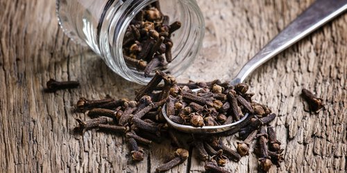cloves spill out of its jar on table