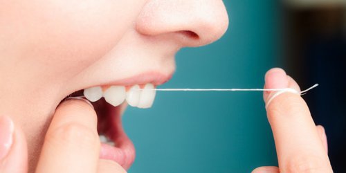 woman using dental floss to clean her teeth