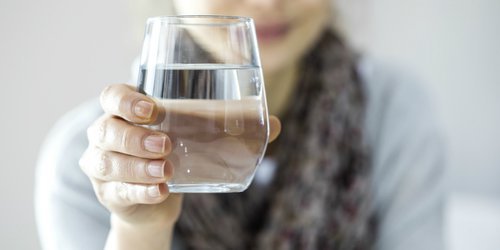 woman holding a glas of water to keep hydrated