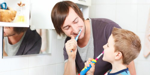 a kid trying new toothbrush that is chose by his father