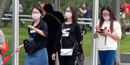 3 women wearing face mask avoiding air pollution walking on the street