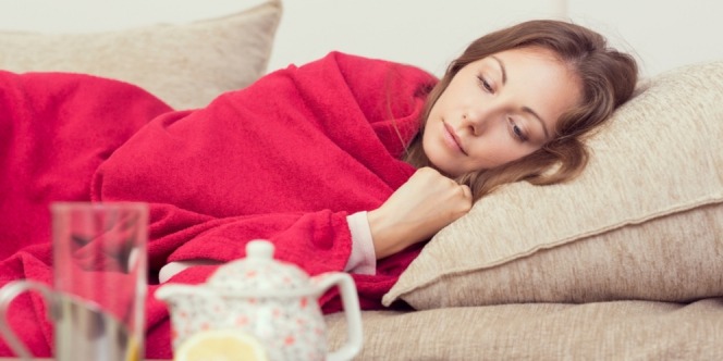 A woman that is feeling sick cover herself with blanket
