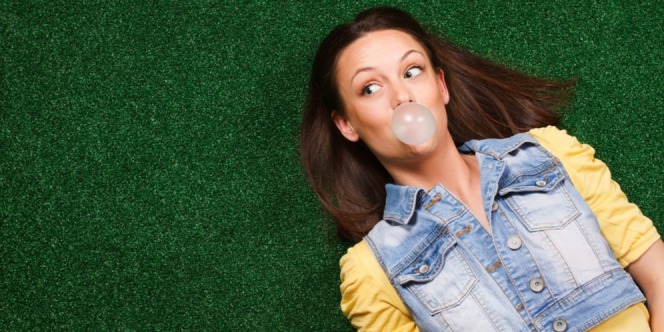 Woman lying on the ground chewing bubble gum