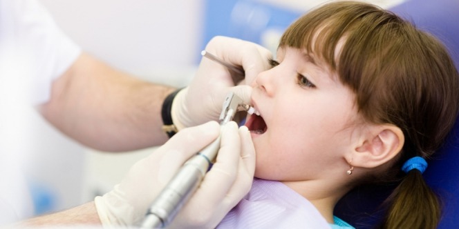 Doctor taking off girls incisor