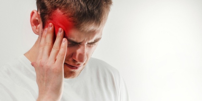 A man feels pain and rubs his head due to migraine